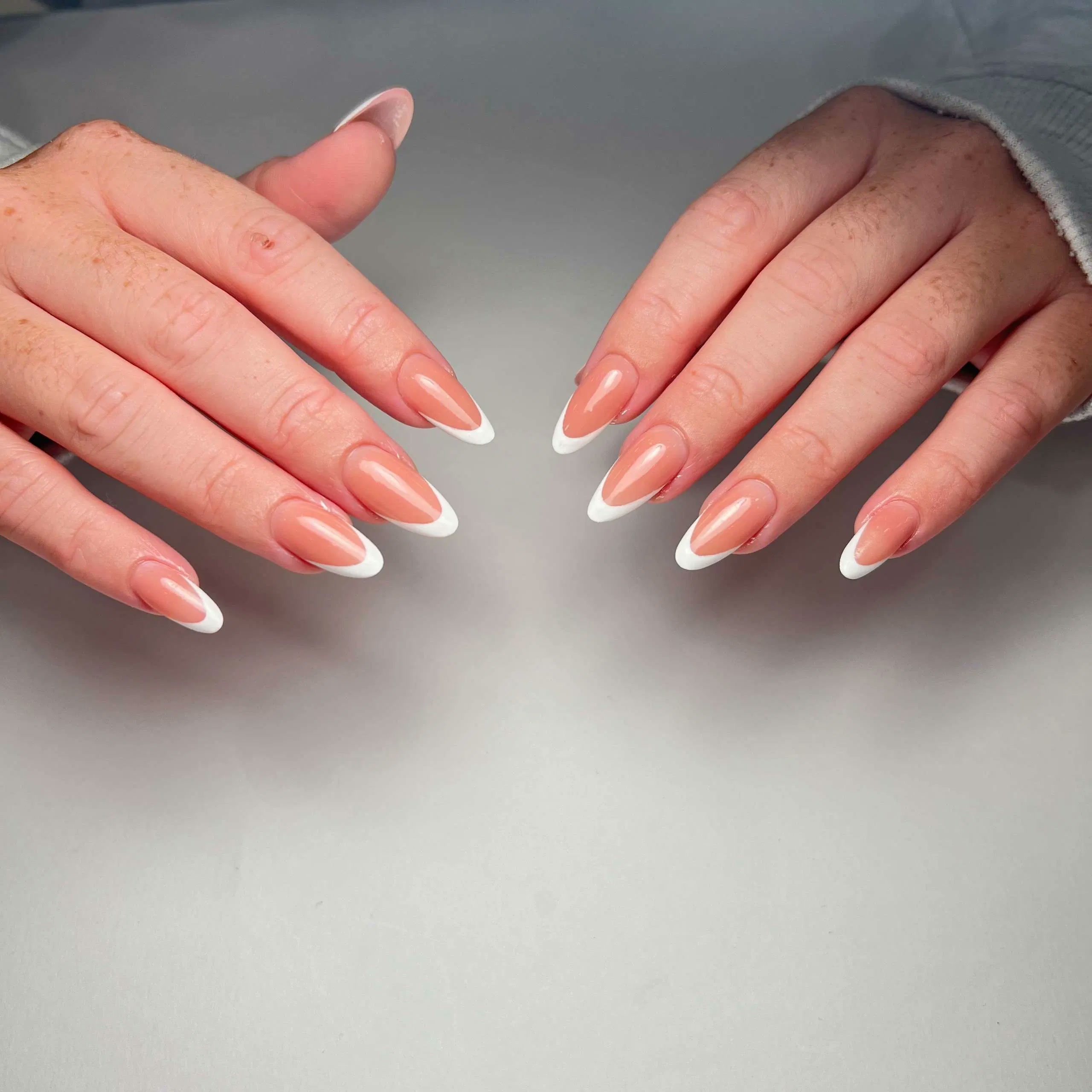 Nude almond nails with delicate white French tips at Aurevia Nails